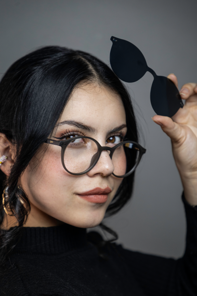 Mujer con gafas formuladas sosteniendo el clip de sol de sus gafas clip-on
